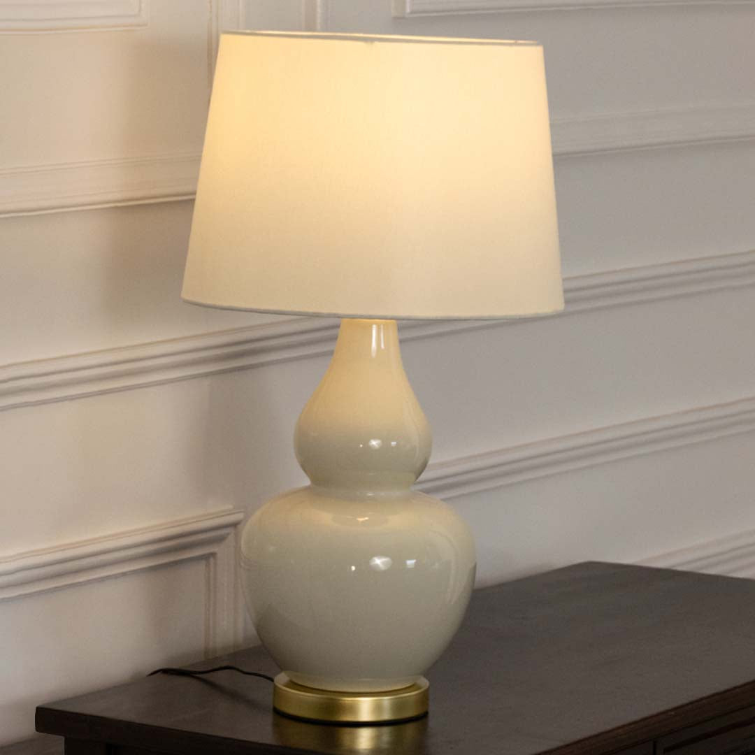 White ceramic table lamp with fabric shade displayed on a wooden console table creating elegant traditional ambient lighting.