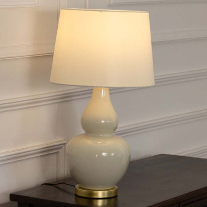 White ceramic table lamp with fabric shade displayed on a wooden console table creating elegant traditional ambient lighting.