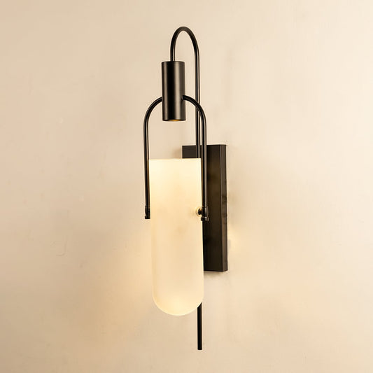 Black metal wall sconce with frosted glass shade glowing softly on white background for ambient lighting.