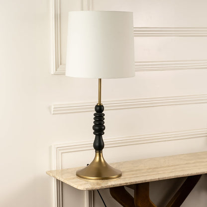 White fabric shade table lamp with black turned wood base and brass accents for elegant bedside and console decor.