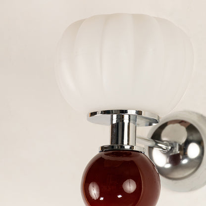 Closeup of white and red glass wall light with chrome finish for modern luxury decor styling spaces.