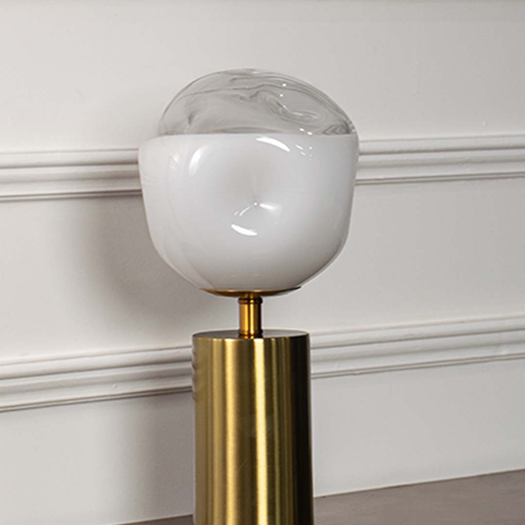 White glass globe table lamp showcasing smooth frosted glass craftsmanship with brass metal base and contemporary design.