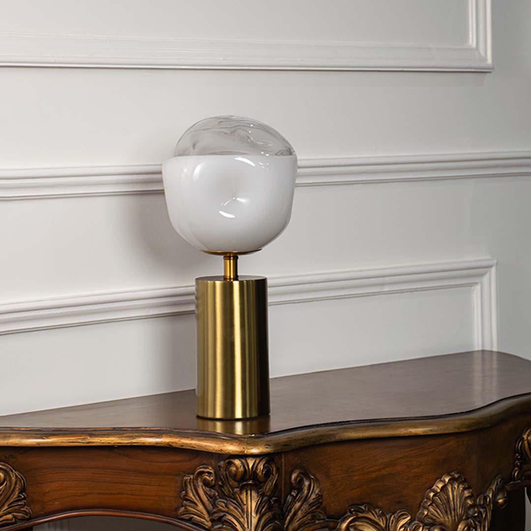 White glass table lamp with brass metal base and globe shade designed for sophisticated modern decor and ambient lighting.