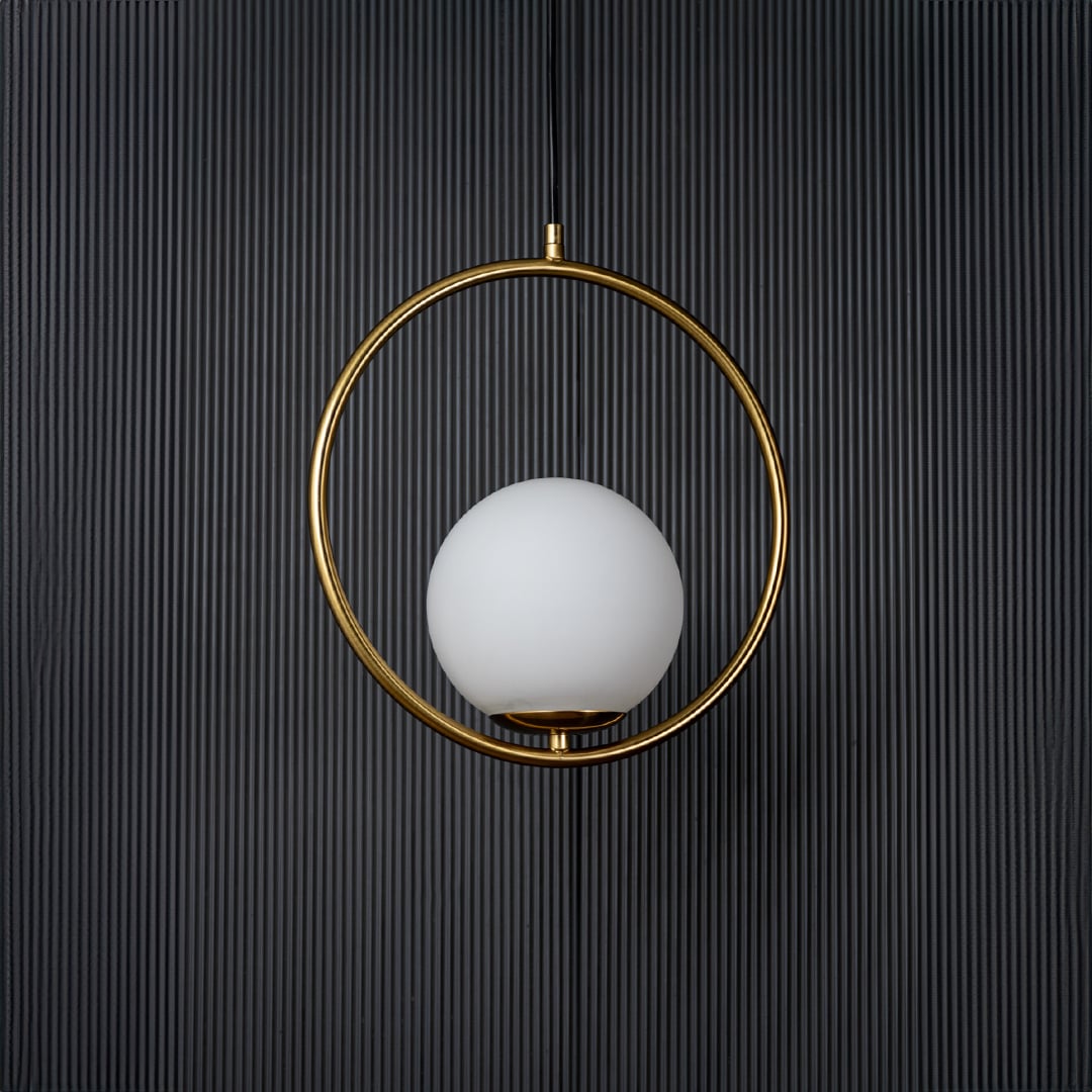 A circular pendant lamp displayed with the light off against a deep black background showing the clean round form and gold ring with subtle reflections.