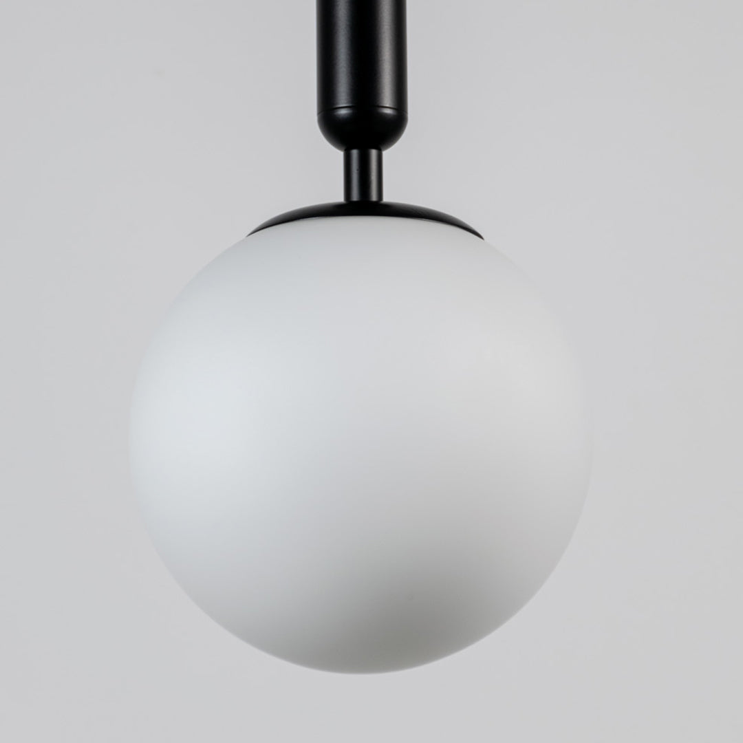 White glass globe pendant light with black metal fixture showcasing smooth opal finish and refined modern craftsmanship.