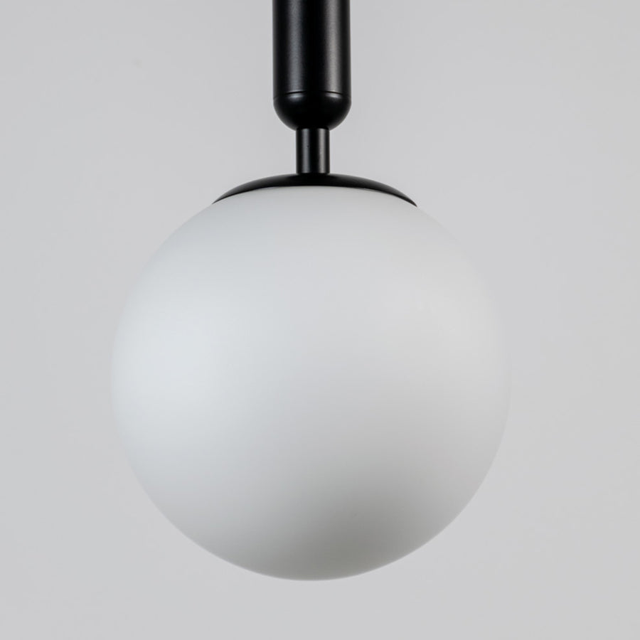 White glass globe pendant light with black metal fixture showcasing smooth opal finish and refined modern craftsmanship.