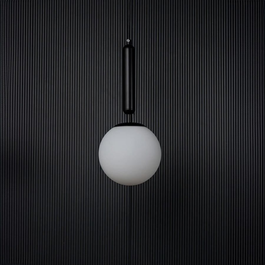 A contemporary pendant light with the bulb off shown on a deep black background highlighting the matte texture and clean geometric shape of the lighting piece.
