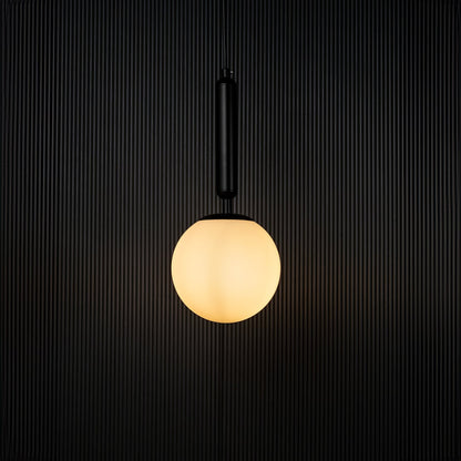 A glowing pendant light with the bulb on set against a dark black backdrop emphasizing its warm illumination and contemporary spherical form.