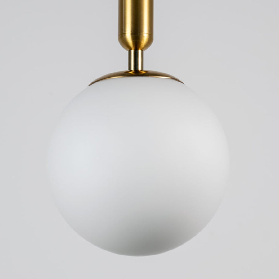 White glass globe pendant light with brass metal fixture showcasing smooth opal finish and refined modern craftsmanship.
