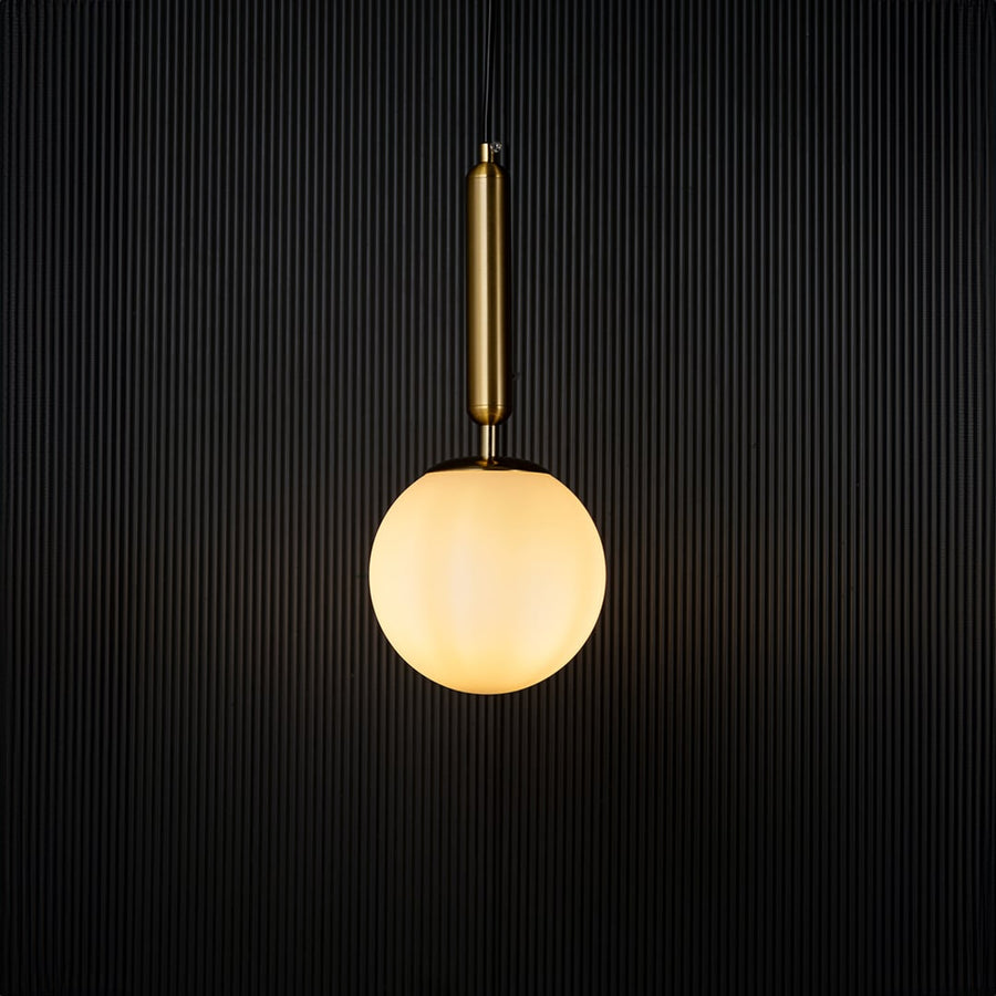 Modern pendant light glowing warmly against a dark background creating a striking contrast that highlights its elegant gold and white finish.