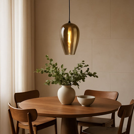 An amber tinted glass pendant light glowing warmly above a wooden dining table creating soft ambient lighting for cozy modern dining room decor.