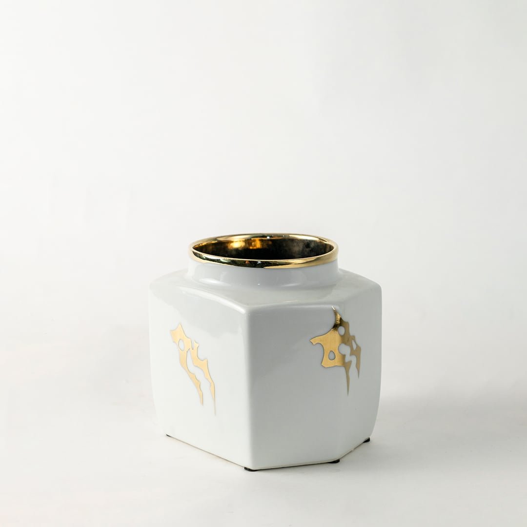 White ceramic decorative storage jar with gold bee artwork and gold rim for elegant shelf styling and home decor.