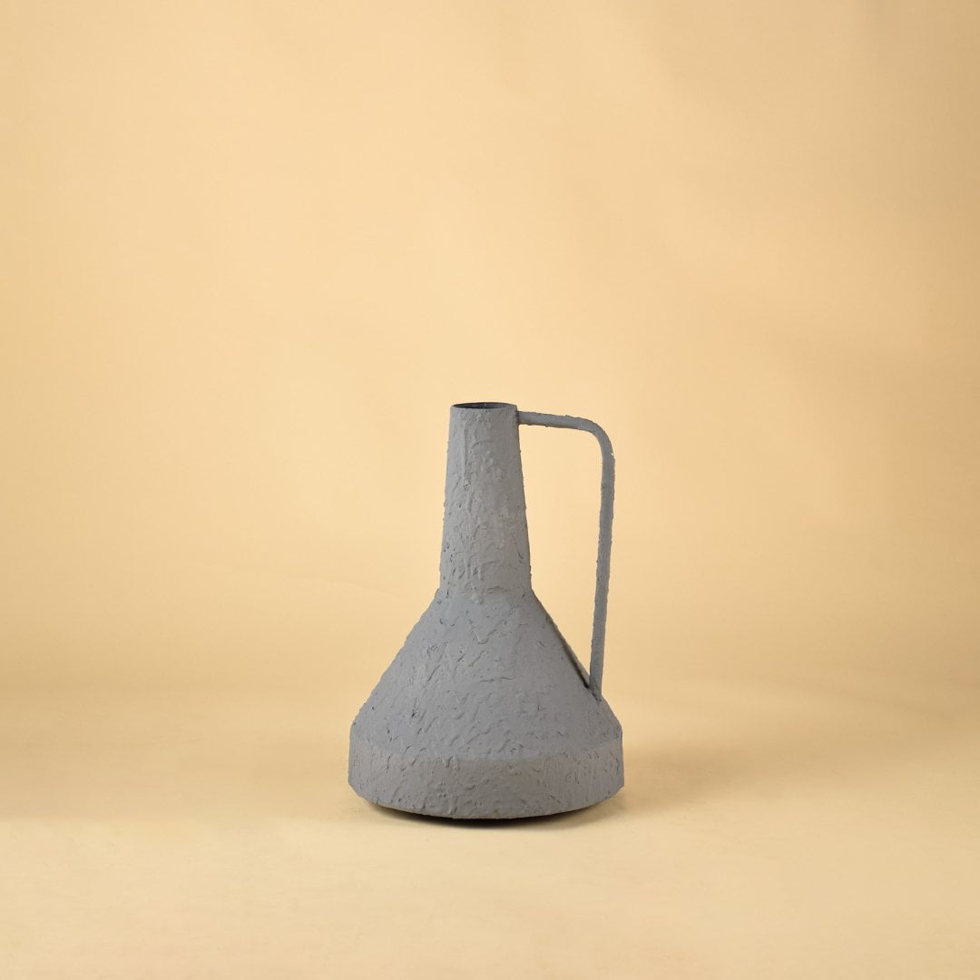Textured gray ceramic jug with metal handle perfect for dried flower arrangements and modern home decoration on soft neutral backdrop.