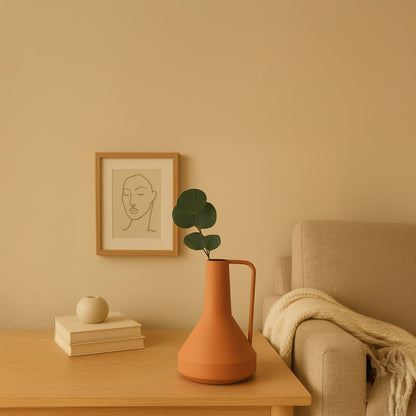 Modern ceramic jugs collection in black terracotta gray and cream with metal handle placed on a wooden table in a cozy living room.