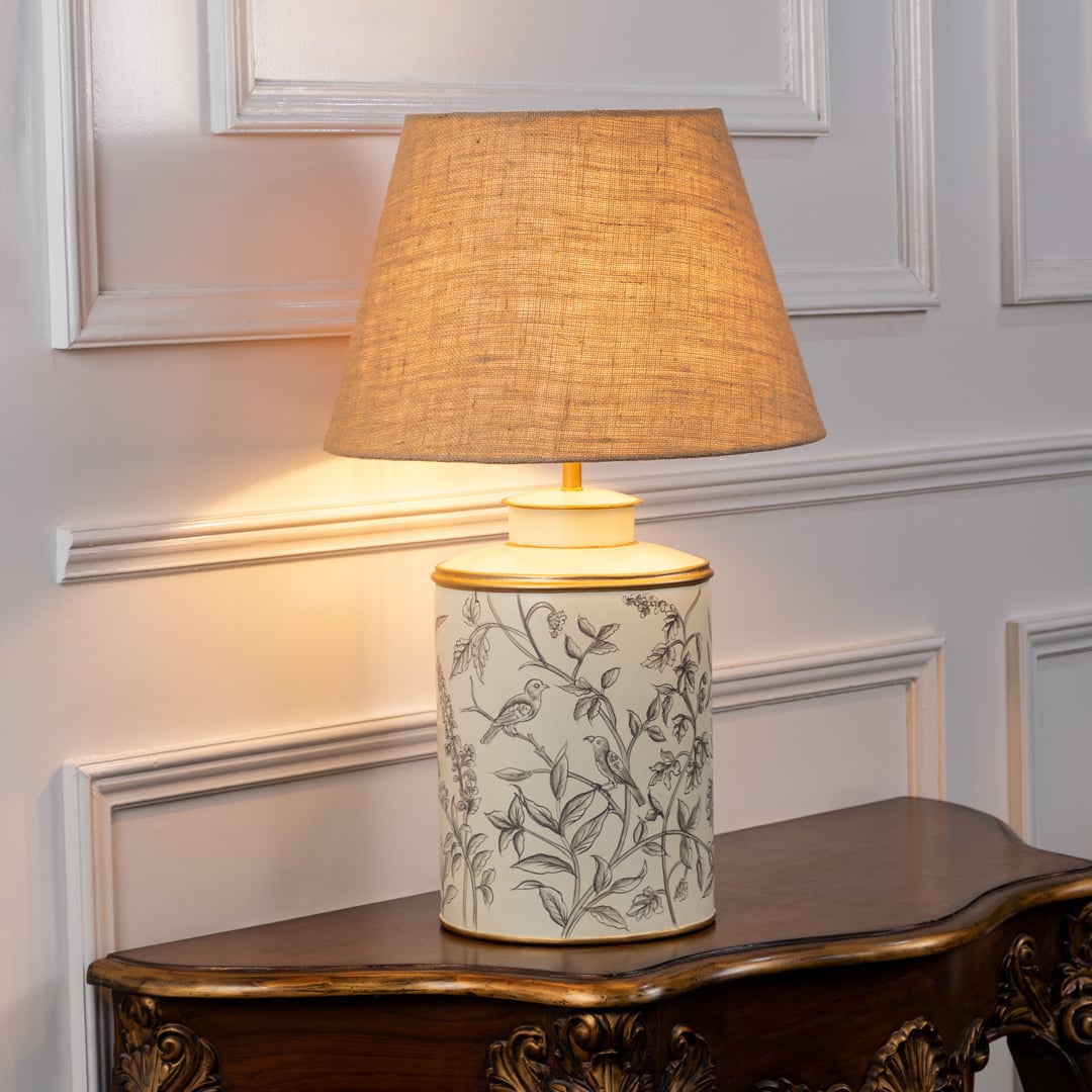 Garden Dusk table lamp illuminated on white background producing warm ambient glow with nature inspired pattern for cozy interiors.