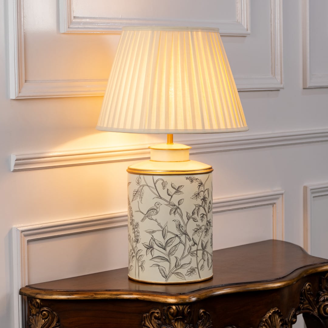 Table lamp featuring a leaf pattern ceramic base with a soft pleated lampshade shown clearly on a white background.