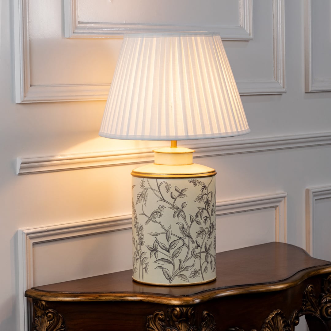 Table lamp featuring a leaf pattern ceramic base paired with a pleated fabric lampshade on a white background.