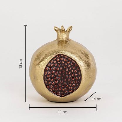 Pomegranate sculpture with gold body and red seed detail measuring 15 cm high 11 cm wide and 14 cm deep on white wall.