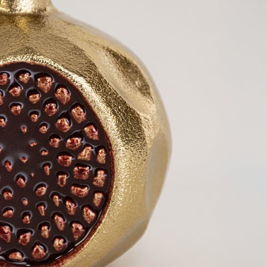 Closeup view of the gold pomegranate decor revealing the raised seed texture and glossy metallic finish