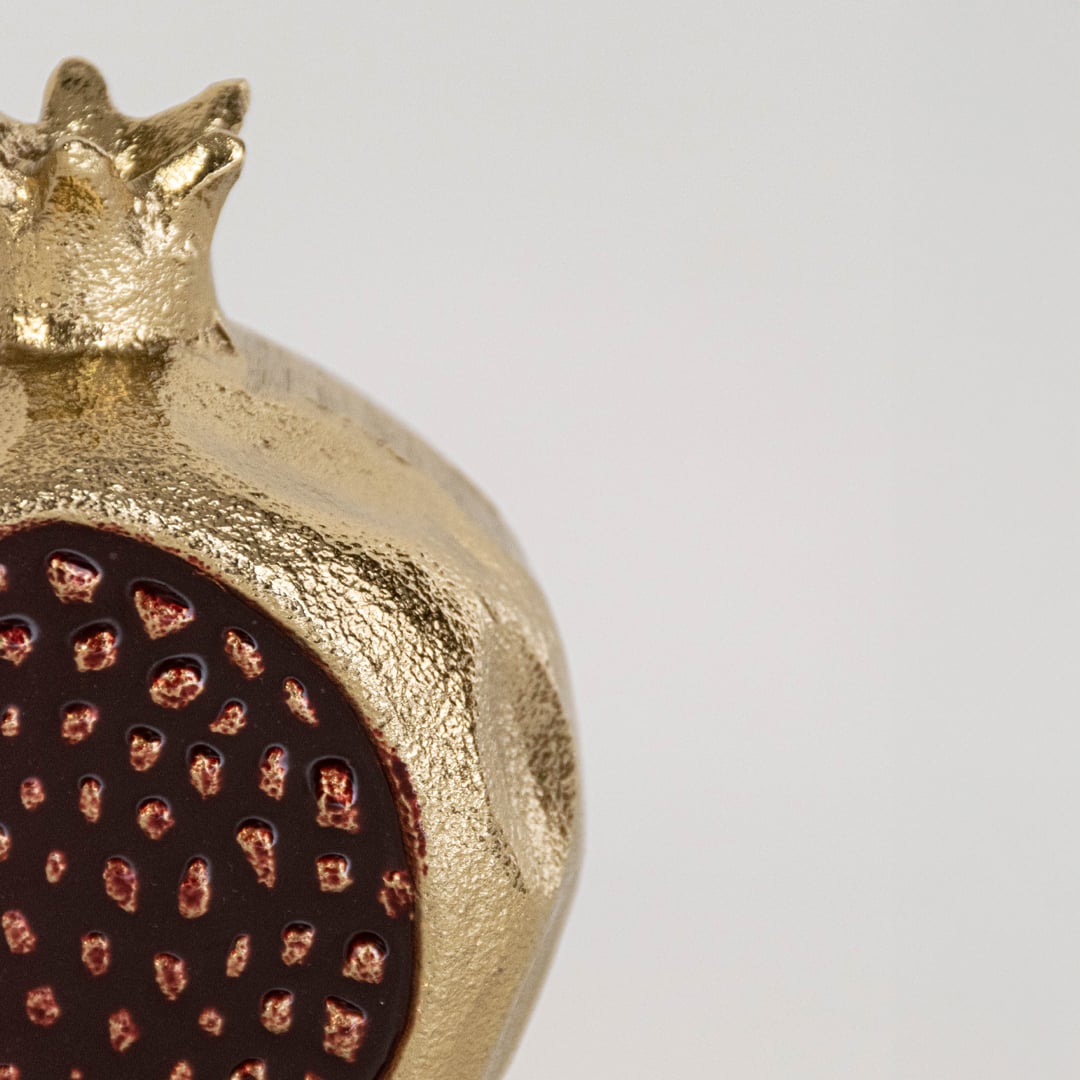Closeup view of the gold pomegranate decor showing the raised seed pattern and detailed surface texture