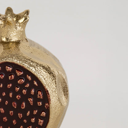 Closeup view of the gold pomegranate decor showing the raised seed pattern and detailed surface texture