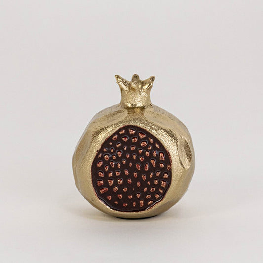 Golden pomegranate decor piece displayed on a clean white background highlighting its textured seed design