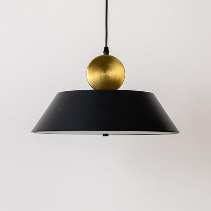Closeup of black metal pendant light with gold sphere detail highlighting smooth finish premium materials and modern lighting design.