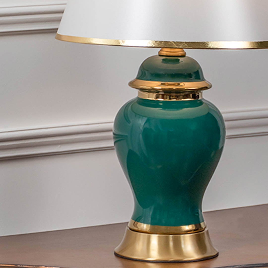 Closeup of modern green ceramic table lamp with golden base and white lampshade for luxury interiors.