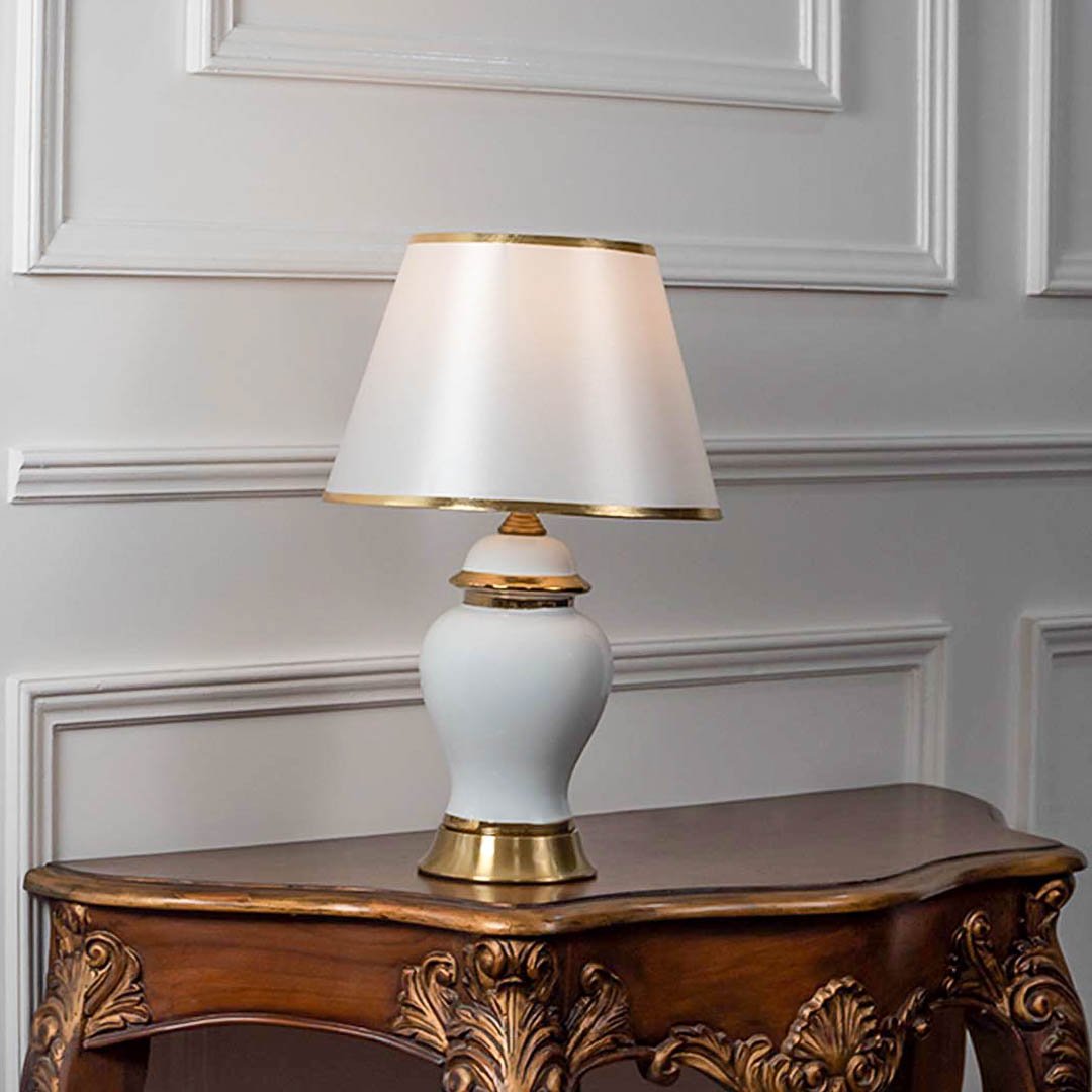 Table lamp with white ceramic base and white fabric shade on wooden table minimal classic lighting for bedroom decor.