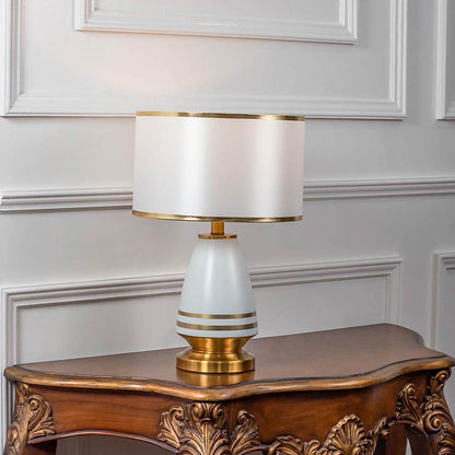 Table lamp with white shade and gold metal base placed on wooden side table ideal for bedroom living room decor styling.