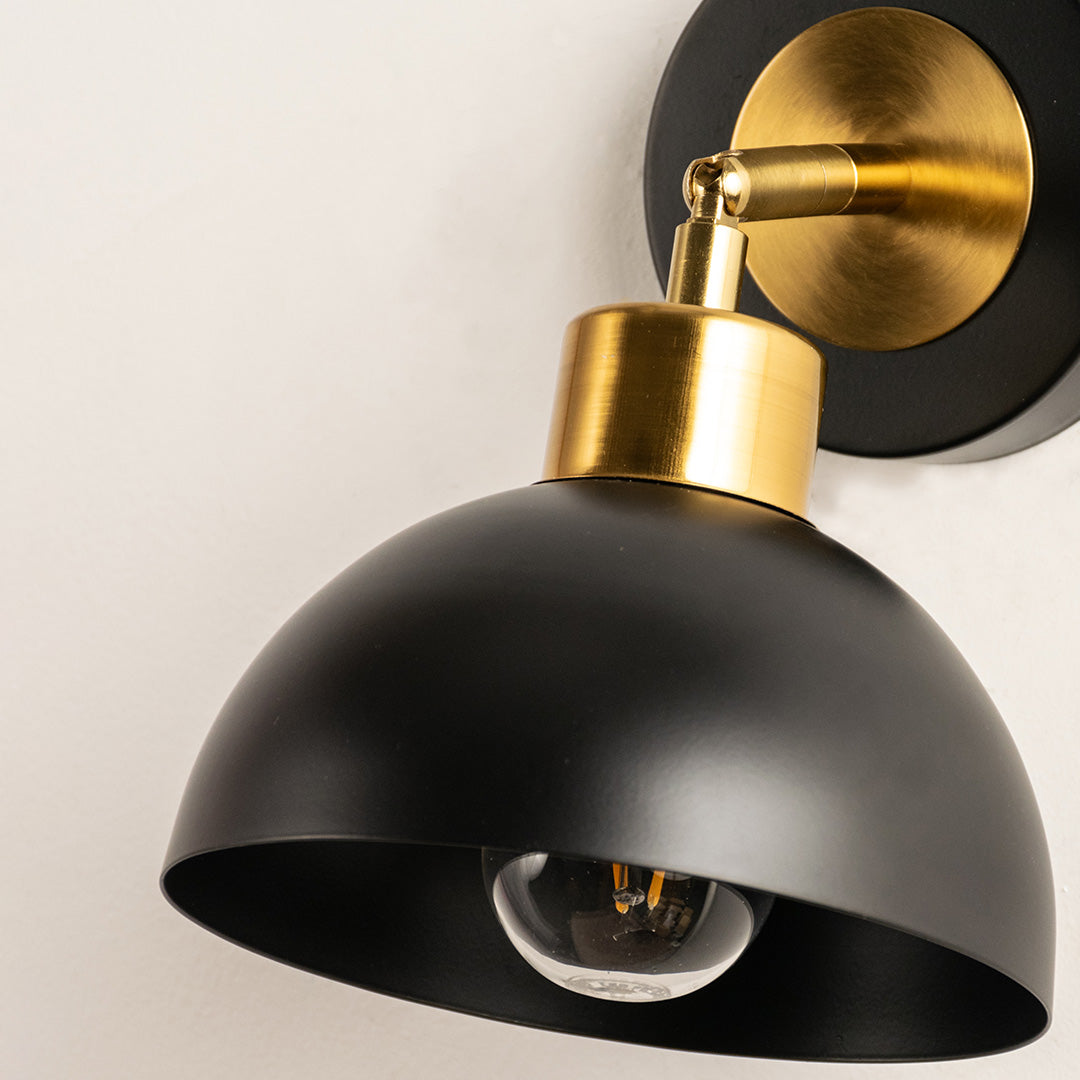 Closeup of black metal wall light with gold holder showcasing smooth finish and premium detailing for modern interior decor styling.