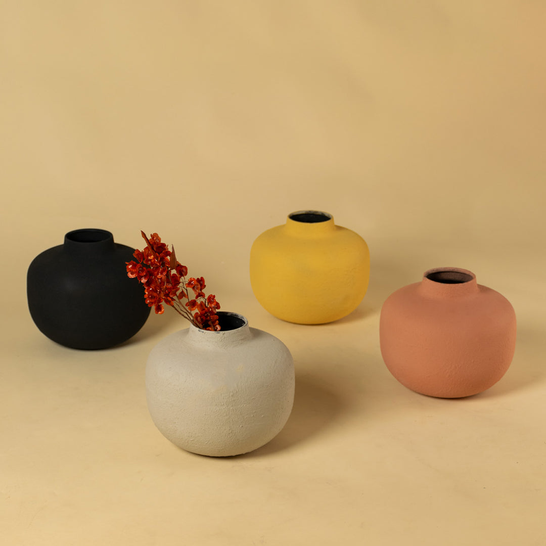 Collection of four colorful matte round metal bud vases for vibrant modern home decor and artistic centerpiece arrangement.