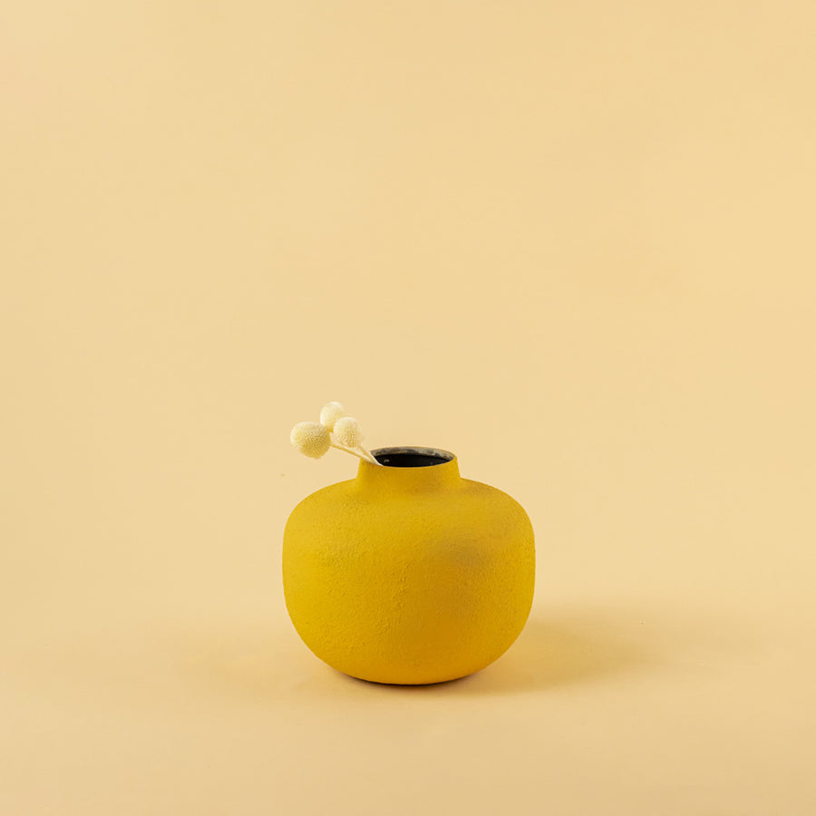 Minimalist matte yellow round metal bud vase with dried stem for modern home decor and elegant shelf accents.