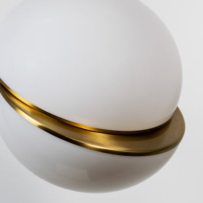 A detailed closeup of the spherical pendant light focusing on the smooth white globe and gold accent band revealing refined craftsmanship and modern decorative appeal.