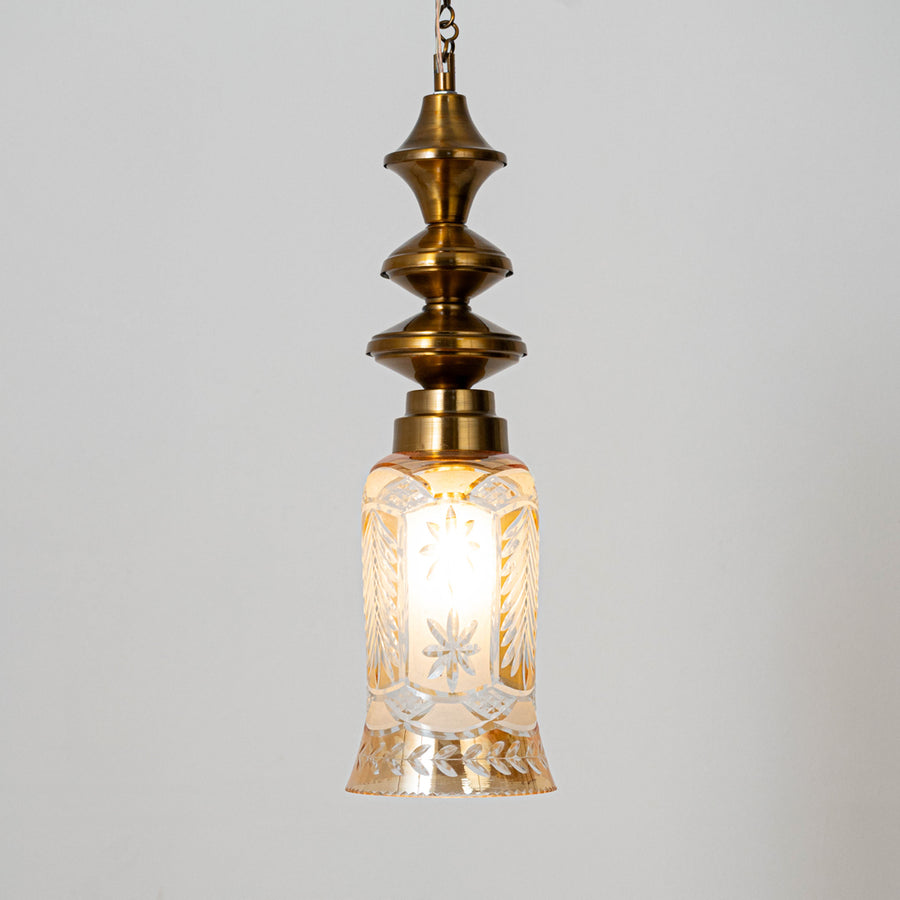 Decorative pendant light in gold metal finish with textured glass shade for dining room or living decor lighting white background.