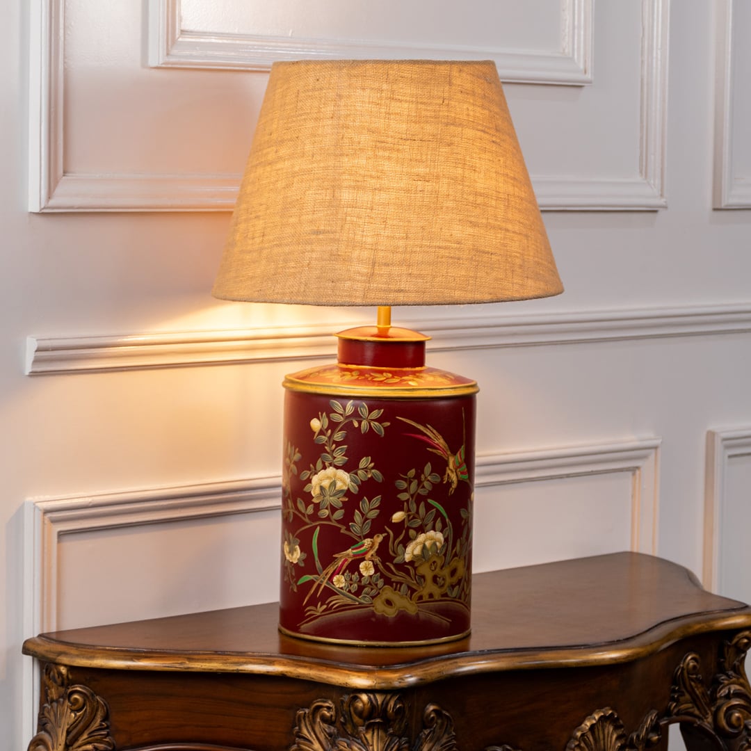 Gilded Phoenix red table lamp on white background with light on showcasing rich pattern warm illumination and artistic interior appeal.