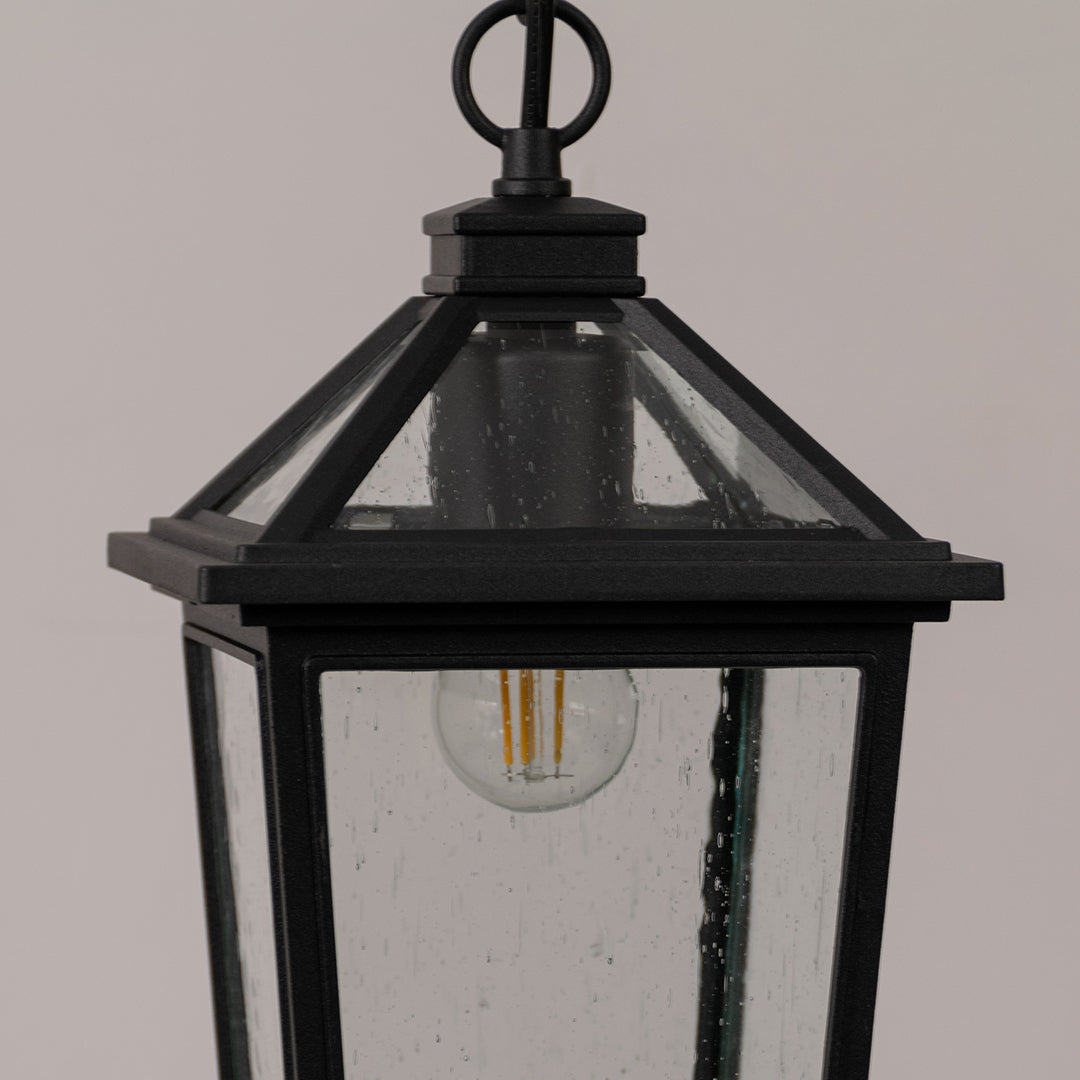 Closeup outdoor lantern in black metal finish with glass panels for entrance or garden decor lighting white background.