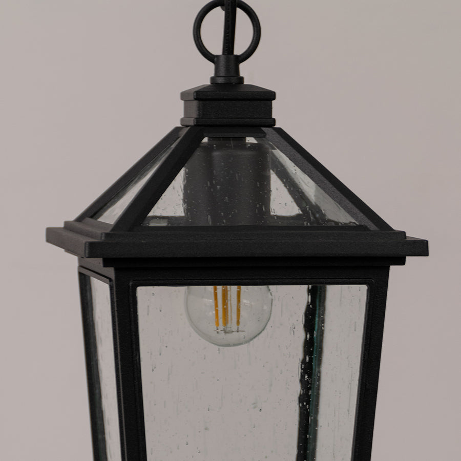 Closeup outdoor lantern in black metal finish with glass panels for entrance or garden decor lighting white background.