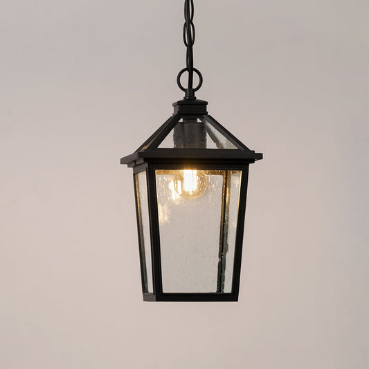 Black outdoor lantern with the light switched on displayed on a white background showing a warm glow through the clear textured glass panels.