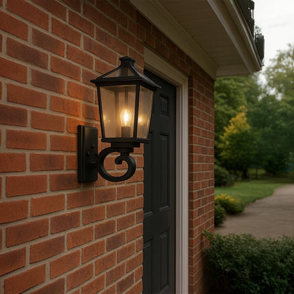 Black outdoor wall lantern with clear textured glass adding warm classic lighting to a modern entryway or garden wall decor.