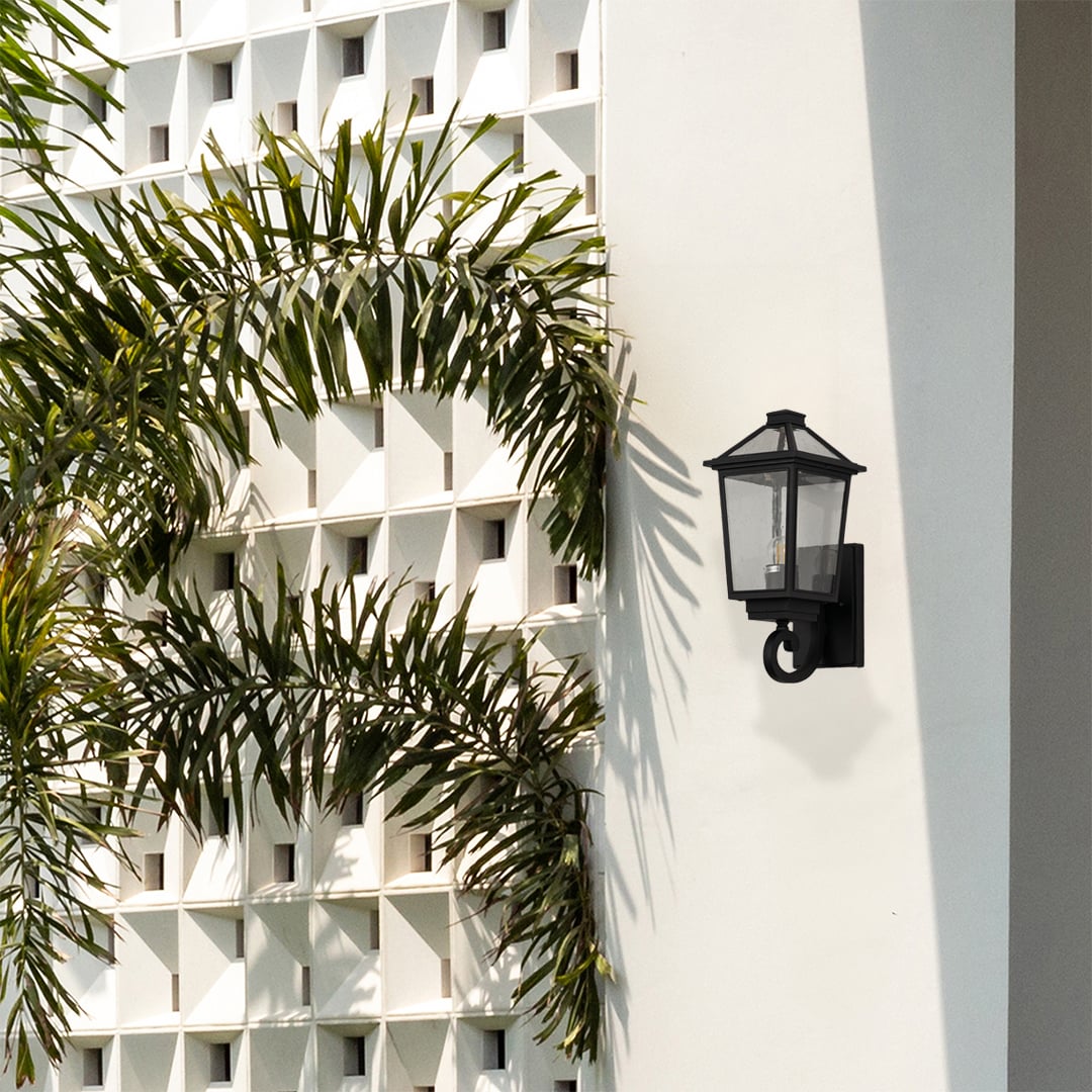 Black outdoor wall lantern styled on an exterior wall creating a warm welcoming glow for porch patio and garden lighting.