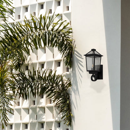 Black outdoor wall lantern styled on an exterior wall creating a warm welcoming glow for porch patio and garden lighting.