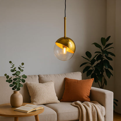 A modern gold and glass pendant light glowing warmly above a beige sofa in a cozy living room with plants and soft cushions creating a calm inviting ambiance.