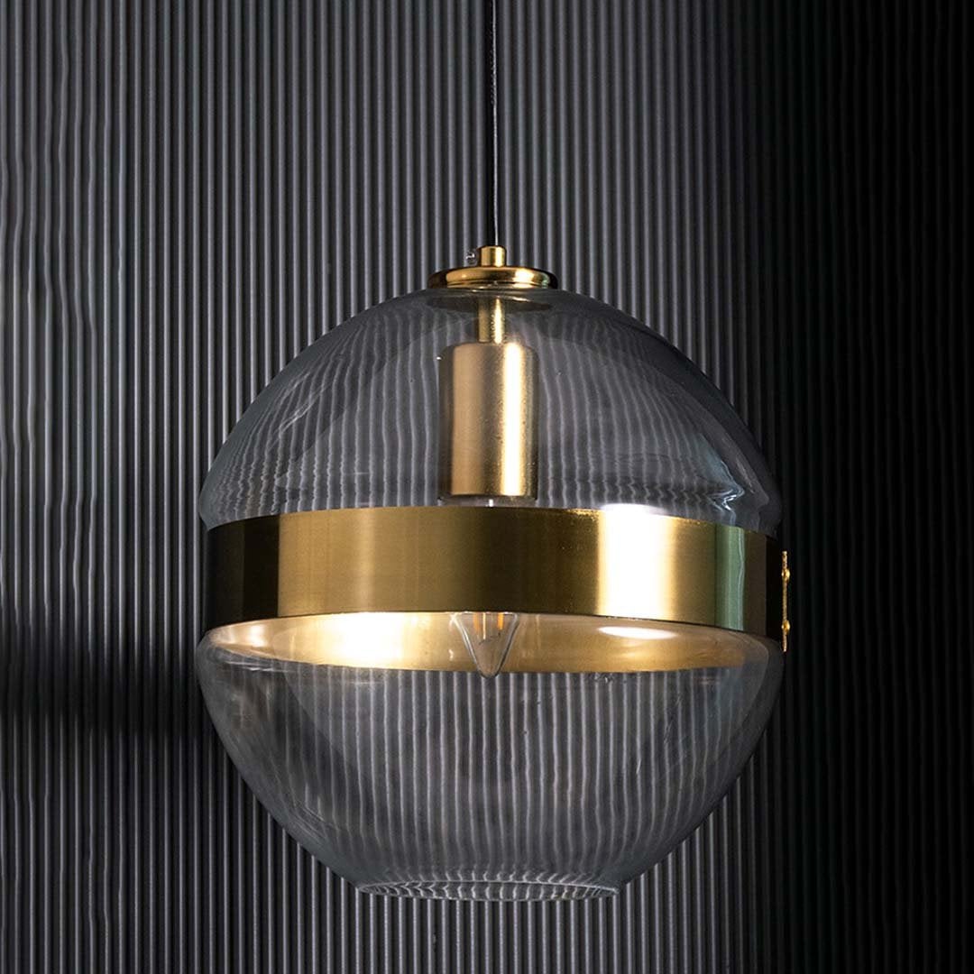 Round glass pendant with gold band shown against a dark ridged backdrop emphasizing its elegant shape and contemporary finish without light.
