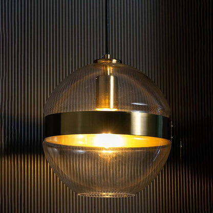 Glowing spherical pendant light with clear glass and gold detailing set against a dark textured background enhancing its warm ambient shine.
