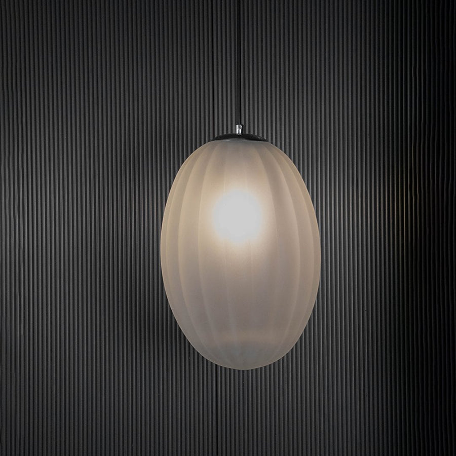Contemporary pendant light with frosted glass shade glowing against a black background.