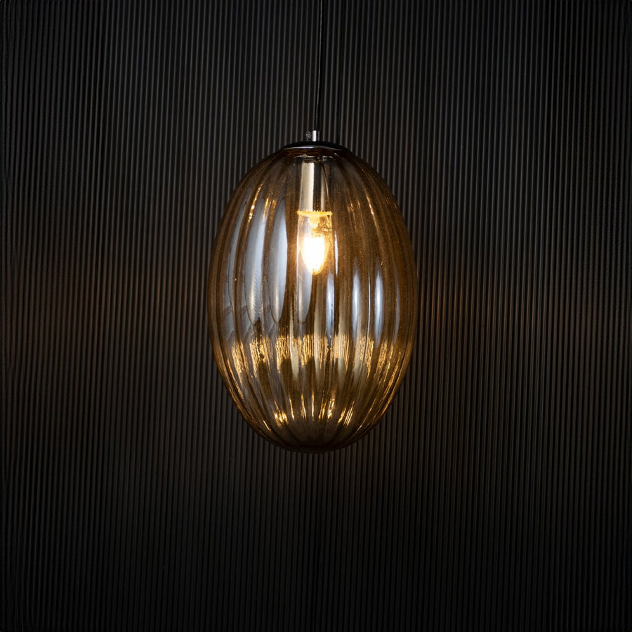 Pendant light turned on against a dark black background creating a soft ambient glow that emphasizes the warm light and elegant structure.