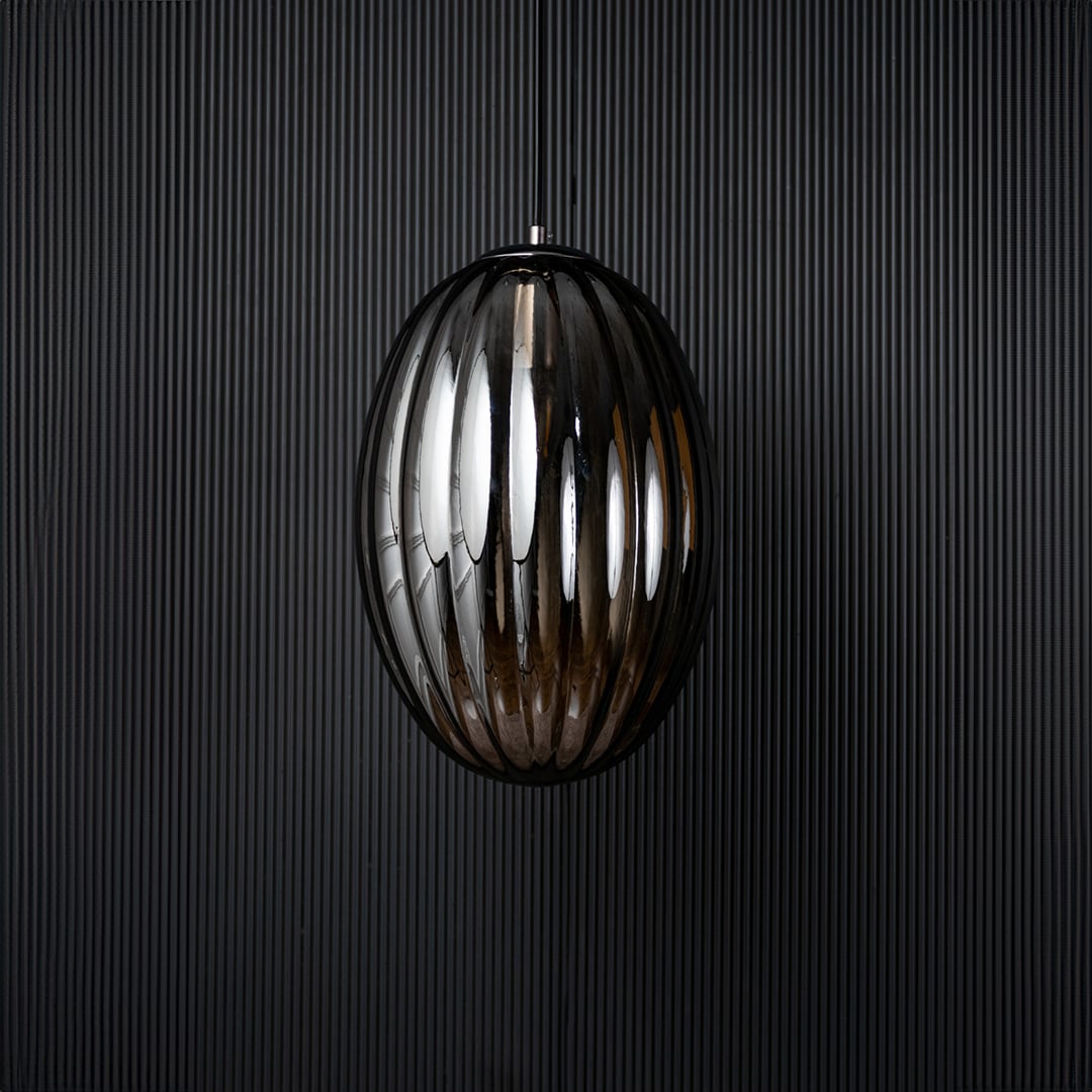 A ribbed oval glass pendant light shown with the light off against a dark background emphasizing the deep reflective finish and sculpted oval design.