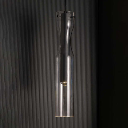 Slim black pendant light with a clear glass exterior shown against a black background highlighting its tall sculpted form with a sleek contemporary finish.