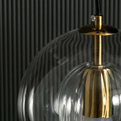 Closeup of glass pendant light showing reflective smoked glass surface gold metal holder and elegant contemporary detailing.